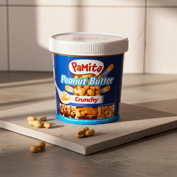 PaMita crunchy peanut butter container on a wooden surface with scattered peanuts.